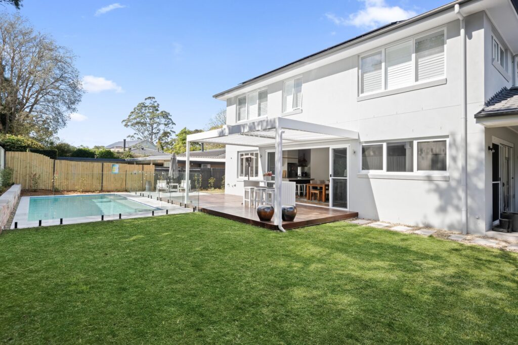 Pearl White louvre roof over St Ives poolside decking from across the yard.