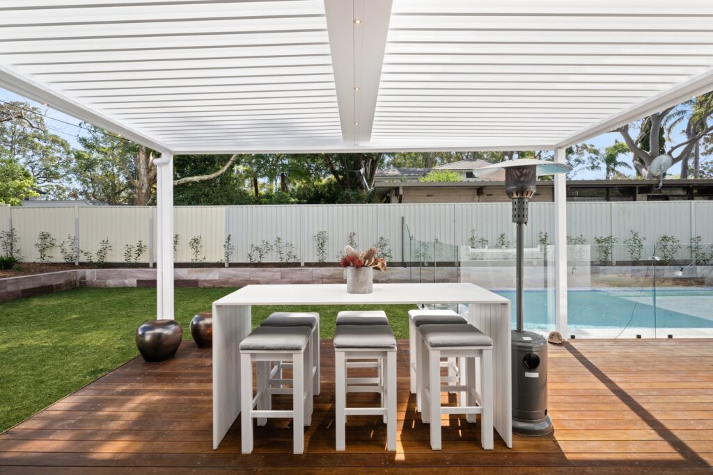 Pearl White louvre roof over St Ives poolside decking with outdoor dining setting.
