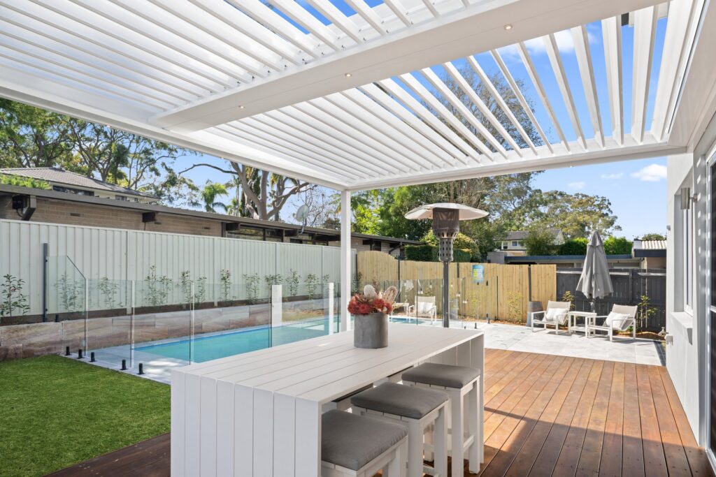 Pearl White louvre roof over St Ives poolside decking with louvres casting shadows.